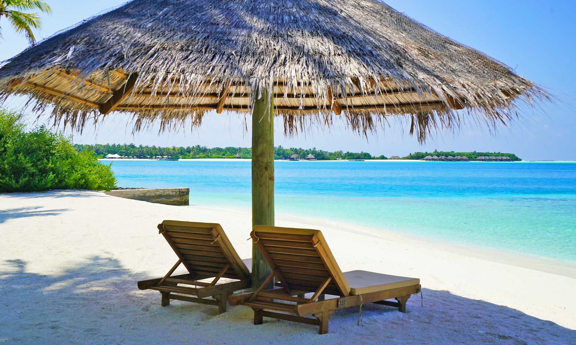 Lounge Chairs Under Thatched Umbrella At The Beach